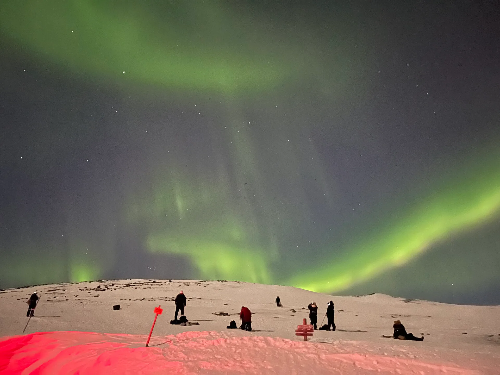 Fotógrafos trabajando la aurora boreal desde una ladera nevada en Abisko