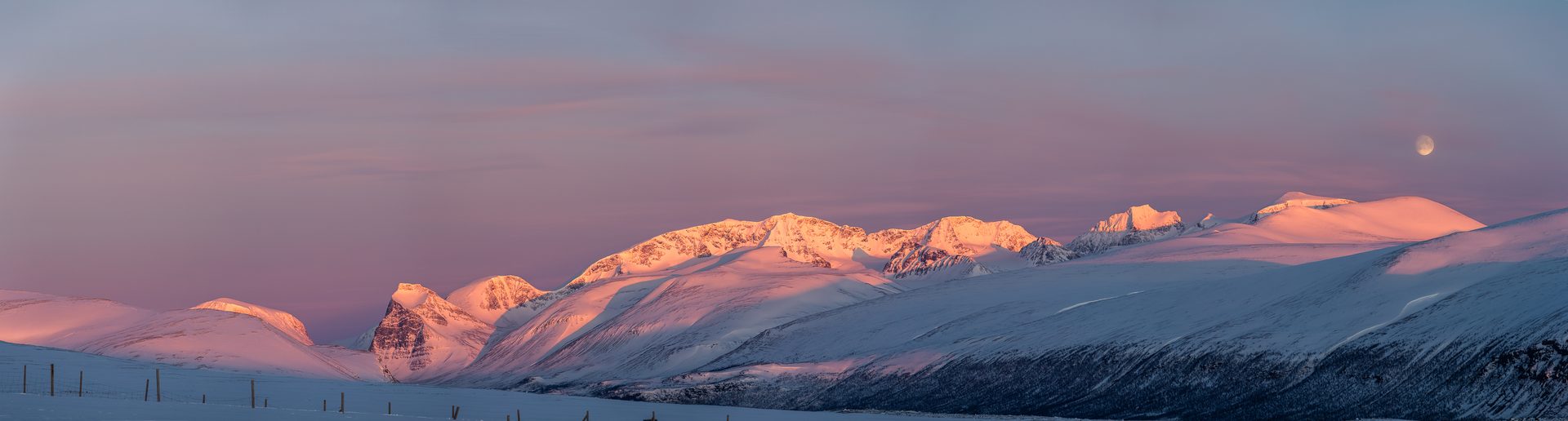 Luz de alpenglow sobre picos árticos nevados en Laponia